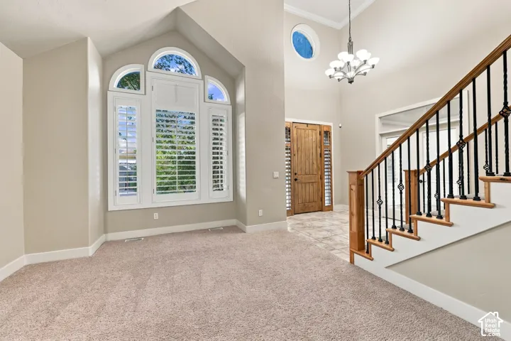 Two-story foyer featuring a chandelier, a natural wood entry door with sidelights, and a staircase with wood treads and wrought iron spindles