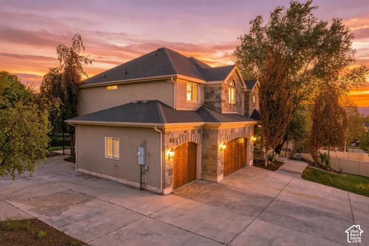 Stucco exterior with stone accents, arched garage doors, and a multi-level roofline