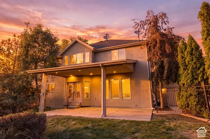 Expansive covered patio with recessed lighting, double glass doors, and a wrought iron fence