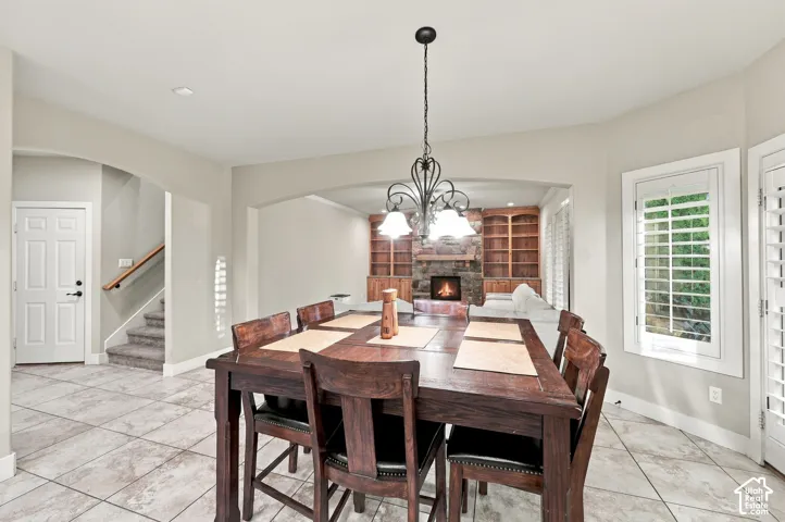 Tiled flooring, overhead chandelier, arched doorways, white panel interior door, and window shutters