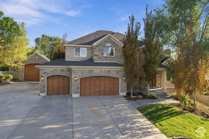 Stone and stucco exterior, arched garage doors, attached two-car garage, detached single-car garage, concrete driveway