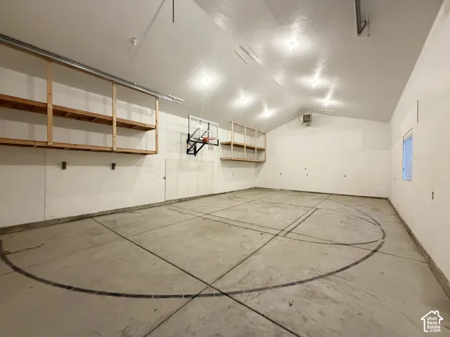 Spacious interior with high vaulted ceilings, concrete flooring, built-in shelving, a mounted basketball hoop, and recessed lighting