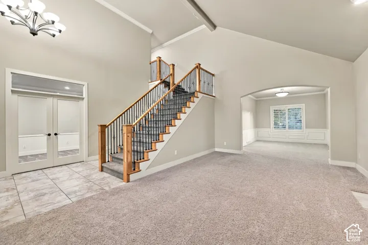 Grand entry with tile flooring, a prominent staircase featuring wood newel posts and wrought iron balusters, and a vaulted ceiling
