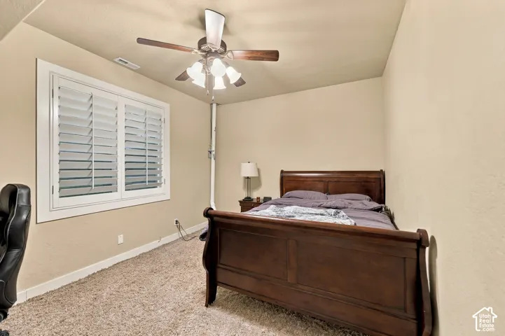 Carpeted room with a ceiling fan, plantation shutters, and light-toned walls