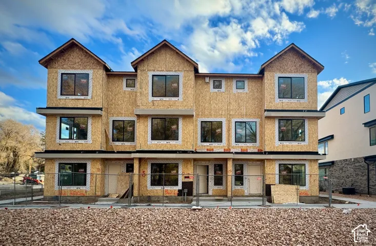 New construction townhome structure with multiple large windows and prominent gabled rooflines
