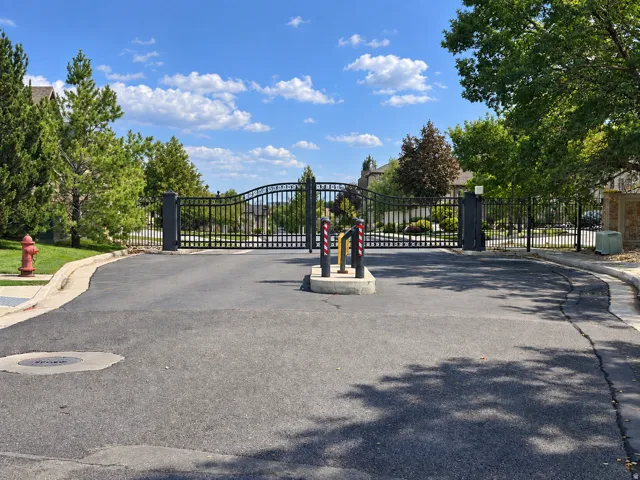 Wrought iron entry gates with stone pillars and paved driveway