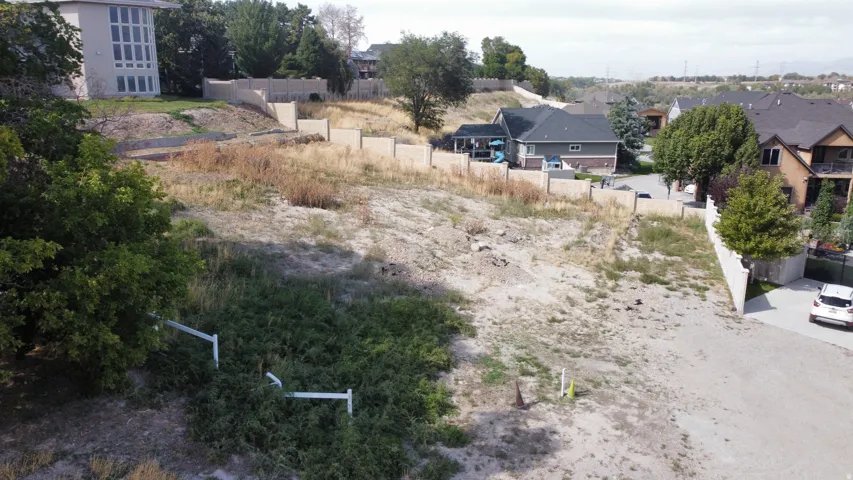 Expansive undeveloped lot with partial retaining walls and surrounding residential properties