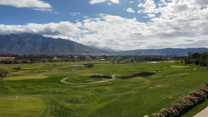 Expansive golf course with manicured greens, undulating fairways, and a distant mountain backdrop