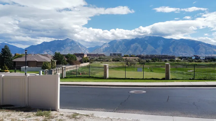 Mountain backdrop, adjacent golf course, paved street, concrete sidewalk, perimeter fencing