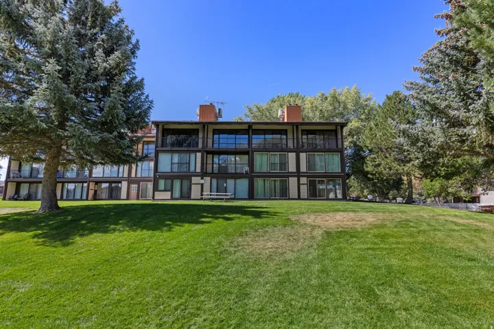 Terraced apartment building with extensive glazing, multiple balconies, and a sloped grass lawn