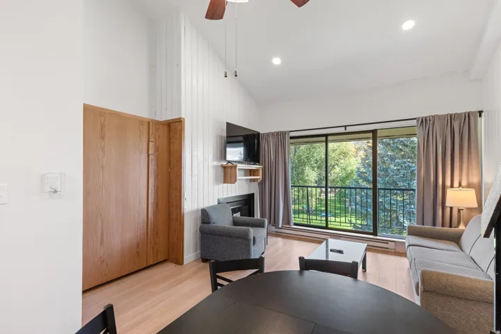 Vaulted ceiling, wood-finish flooring, full-height sliding glass doors, built-in fireplace, and wood-paneled feature wall