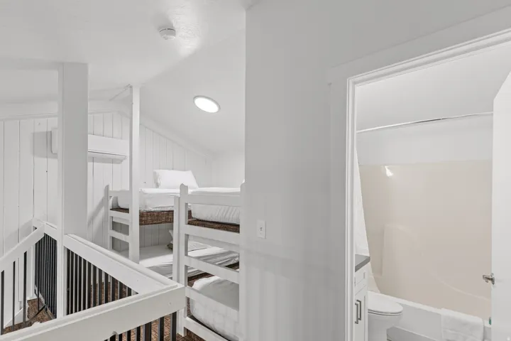 Built-in bunk beds, sloped ceiling, recessed lighting, wall-mounted air conditioning unit, and a full bathroom with a shower-tub combination