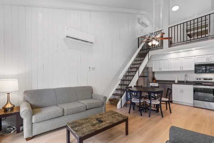 Wood-finish flooring throughout, white vertical paneling, and an exposed wood staircase with black metal railings