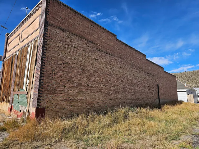 Brick exterior wall with decorative upper paneling and wood-paneled sections