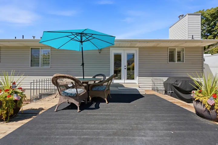 Expansive wood deck with a durable floor covering, direct access through French doors, and a neutral siding exterior