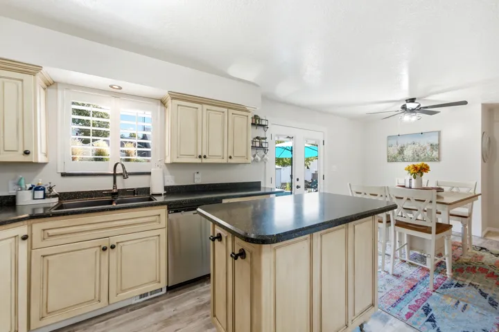 Kitchen featuring cream cabinetry with dark hardware, dark countertops, a center island, and wood-finish flooring