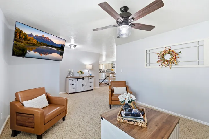 Recessed ceiling lighting, ceiling fan with wood-finish blades, and light-colored carpeting