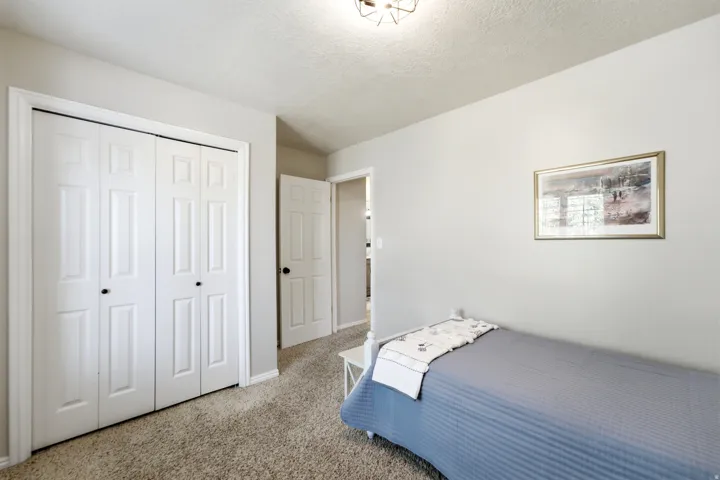 Light neutral wall paint, textured ceiling, carpet flooring, bi-fold closet doors, and a flush mount light fixture