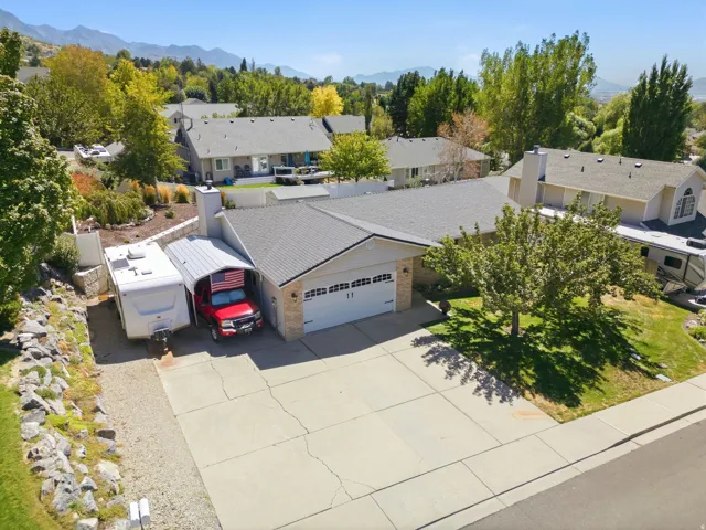 Single-story residence featuring a two-car garage, an attached carport, and a gravel side yard