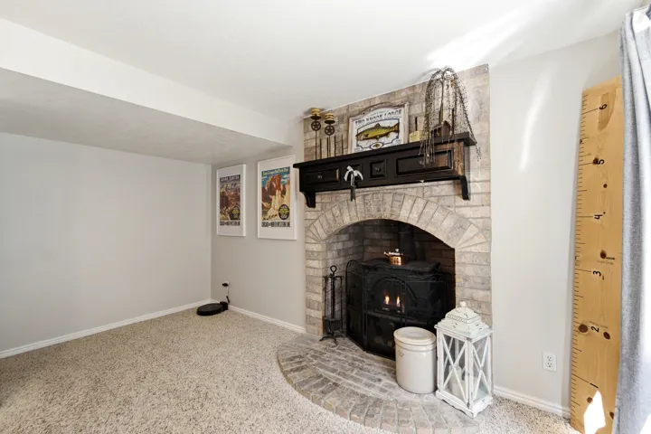 Brick fireplace with an arched opening, a black wood mantel, and a brick hearth
