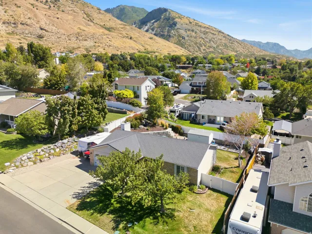 Pitched shingle roof, mature landscaping, and an attached garage