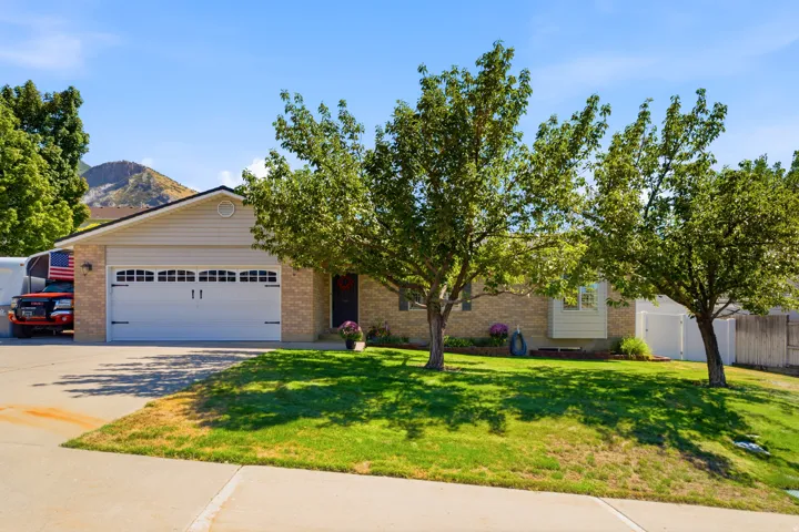 Brick exterior with a peaked roofline, attached garage, and mature front yard landscaping