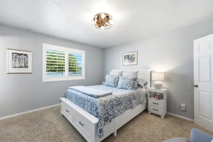 Carpeted room featuring a ceiling-mounted light fixture, a window with plantation shutters, and light-colored walls