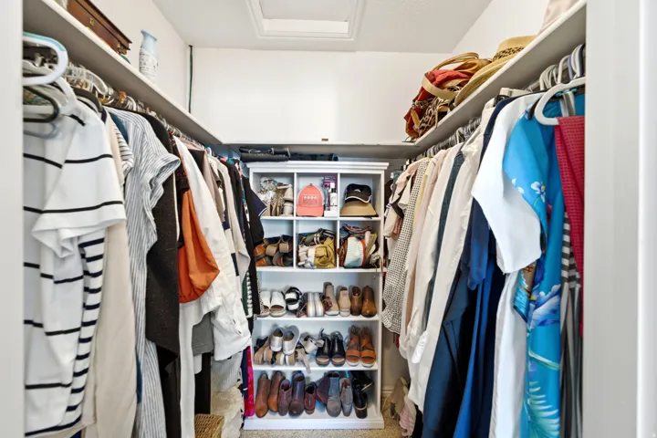 Walk-in closet featuring extensive hanging space, built-in shelving, and upper storage ledges