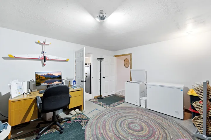 Room featuring white walls, a corner desk with wood-finish cabinetry, and a ceiling-mounted light fixture