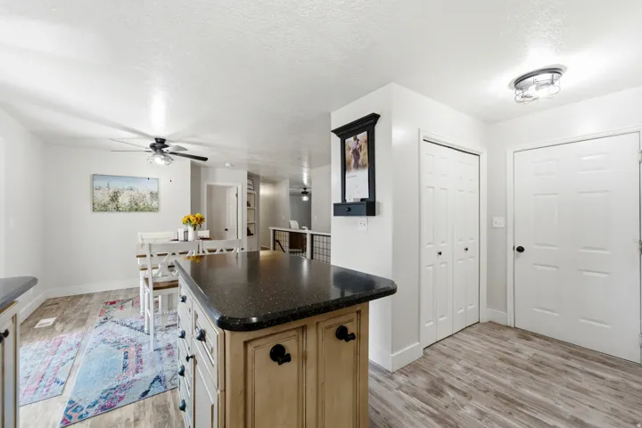 Kitchen island with dark speckled countertop, light wood-finish cabinetry, and black hardware
