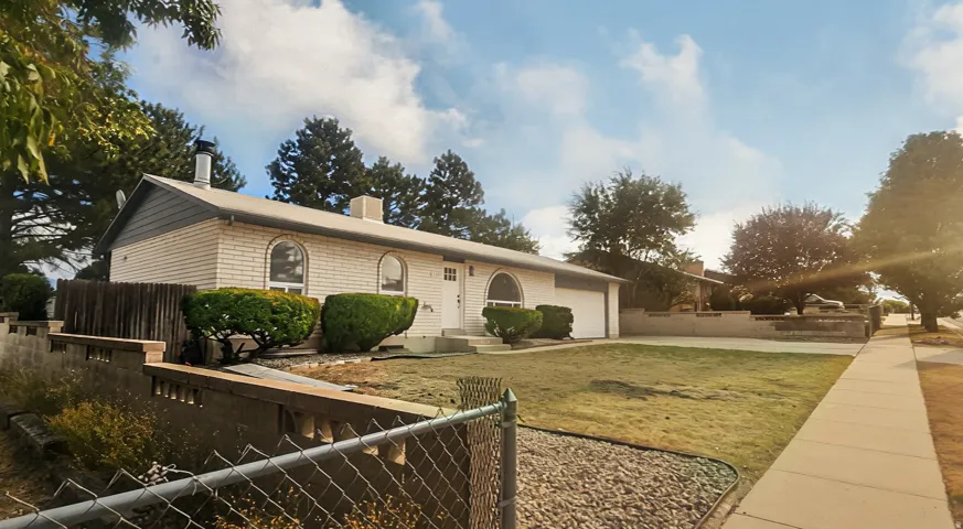 White brick exterior with arched windows, an attached garage, and a concrete sidewalk