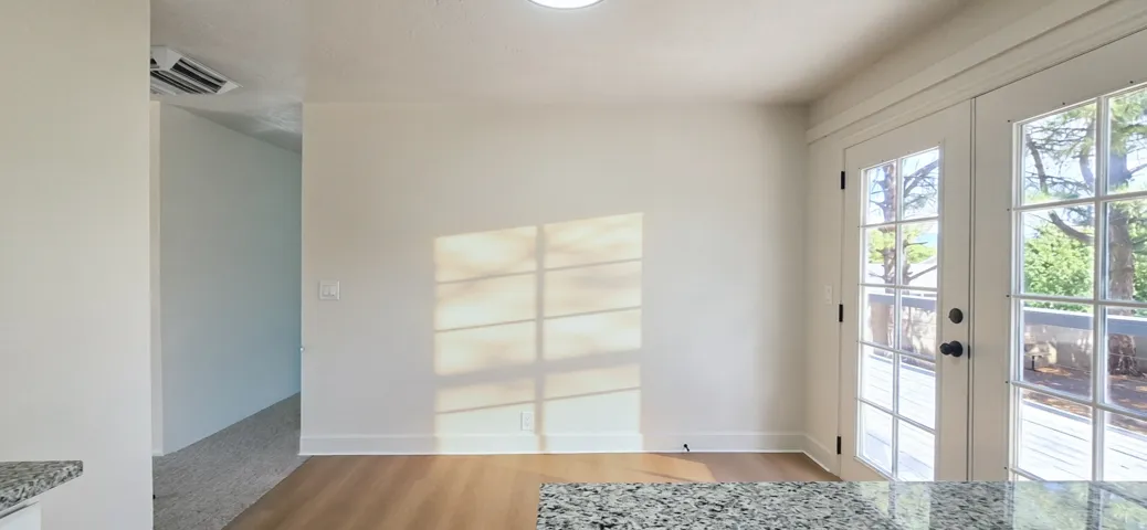 Hardwood-finish flooring, recessed ceiling lighting, granite-look countertop, and double French doors with transom detailing