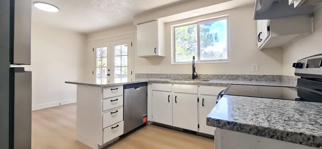 Modern kitchen featuring white cabinetry, stone-finish countertops, and stainless steel appliances