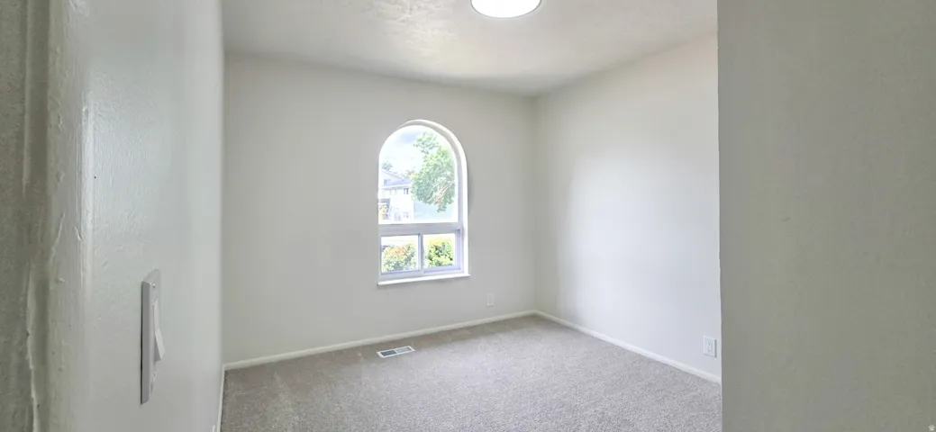 Arched window, gray carpet, neutral wall finishes, flush mount ceiling light