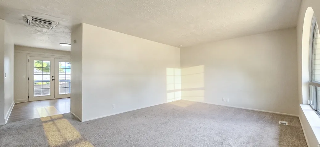 Carpeted living area featuring an arched window, a wall divider, and recessed lighting