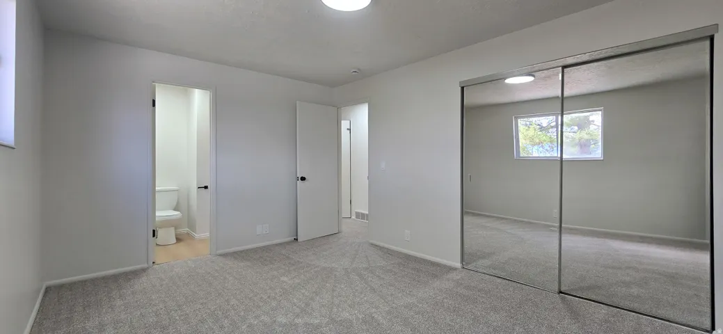 Light gray carpeted flooring, mirrored sliding closet doors, and recessed lighting