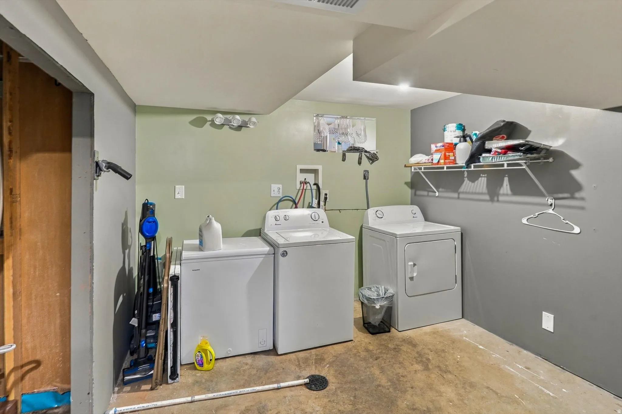 Dedicated laundry area with a washer, dryer, utility sink, and wall-mounted shelving