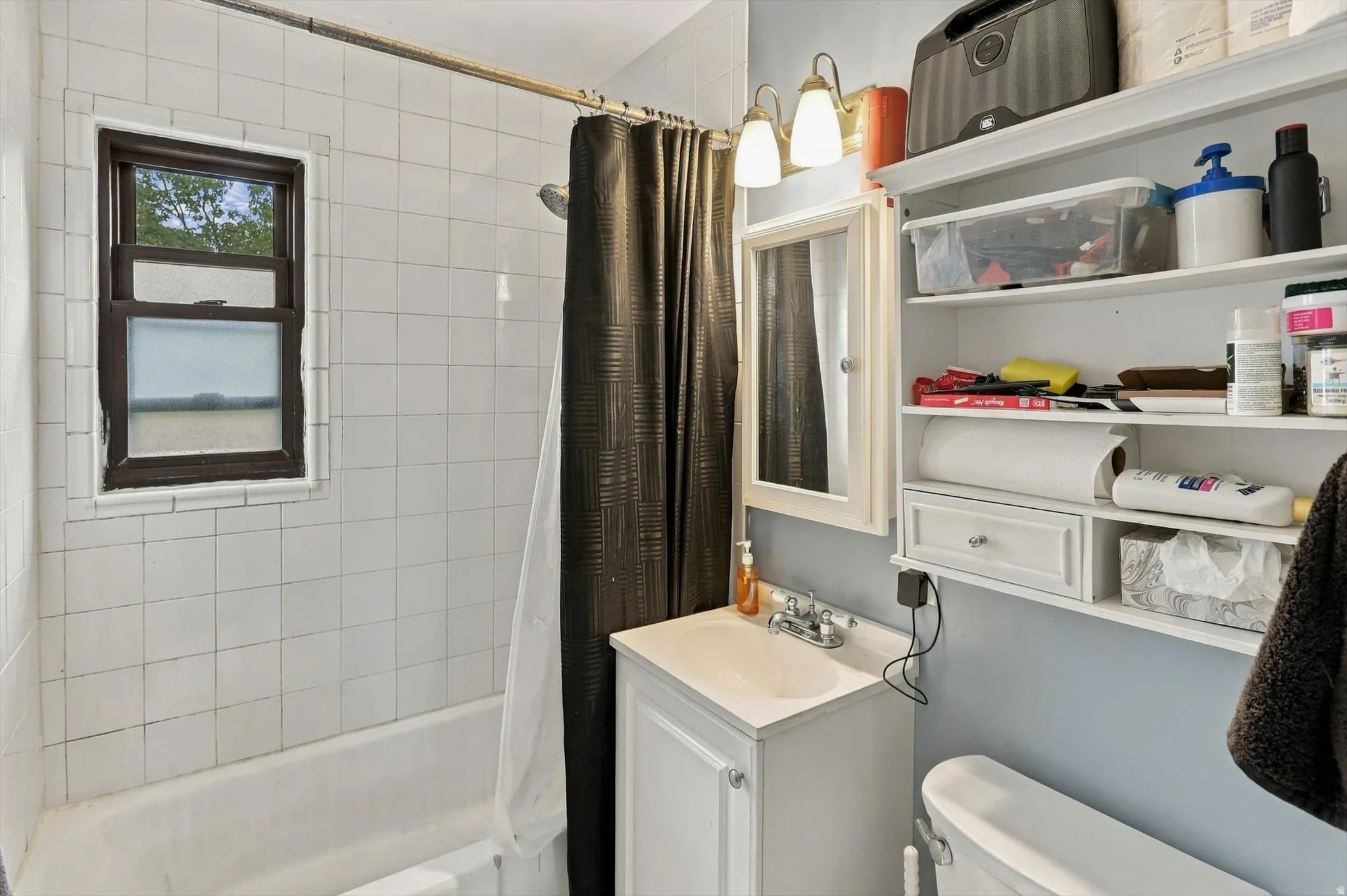 Bathroom featuring a white subway tile surround, built-in bathtub, and a vanity with an integrated sink