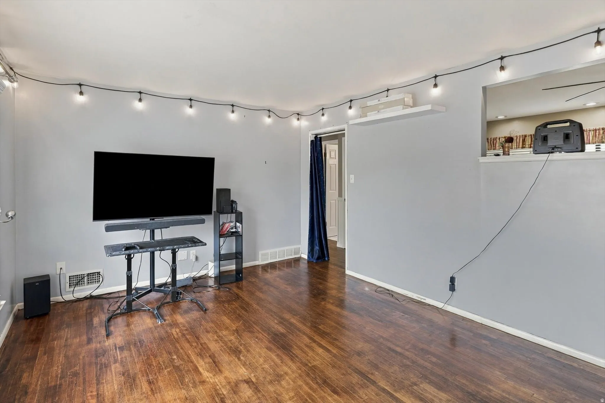 Wood-finish flooring throughout, light gray wall finishes, and a pass-through opening