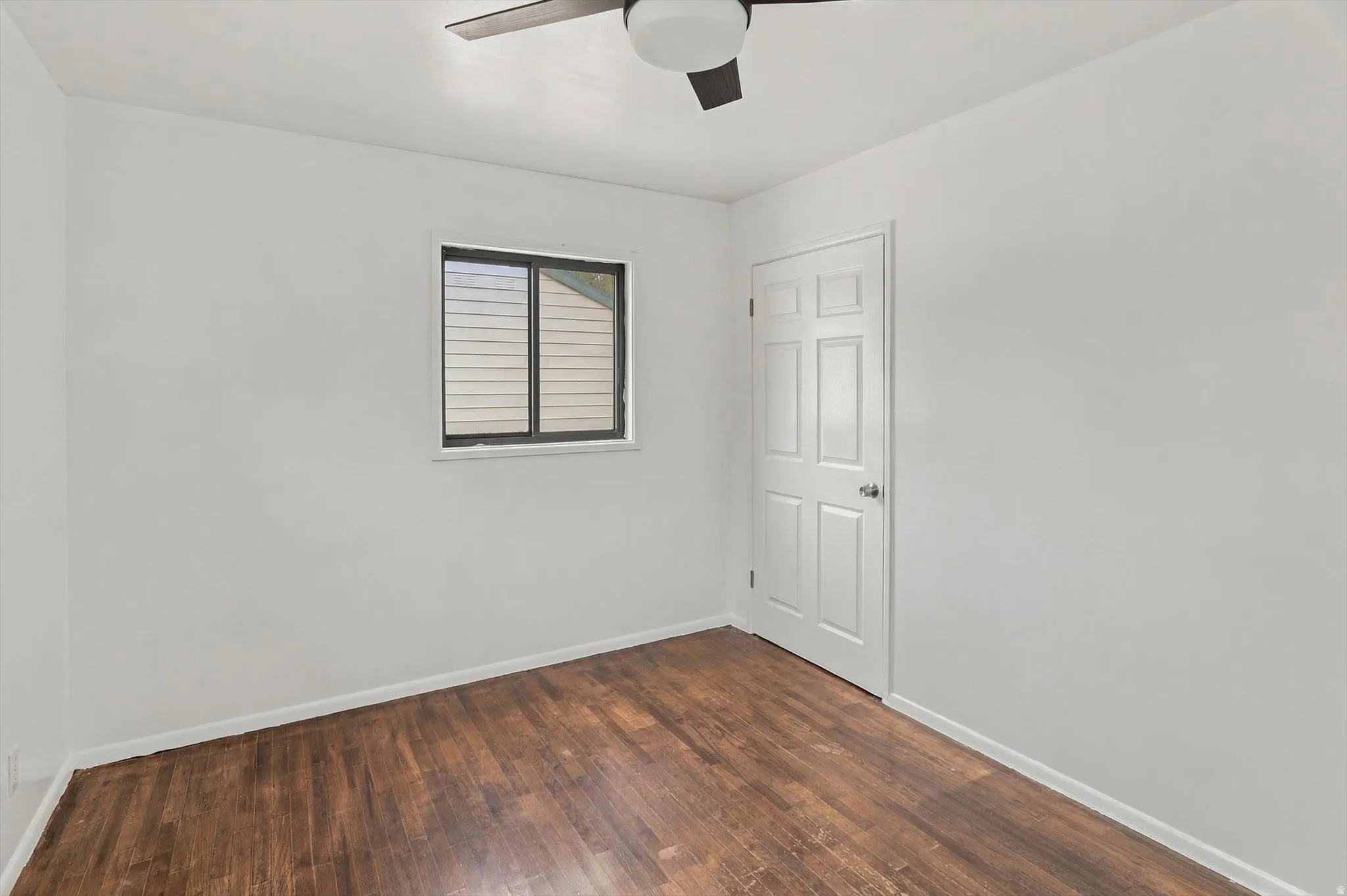 Wood-finish flooring, white walls, and a ceiling fan