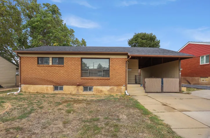 Brick exterior with a dark shingle roof, covered carport, and concrete driveway