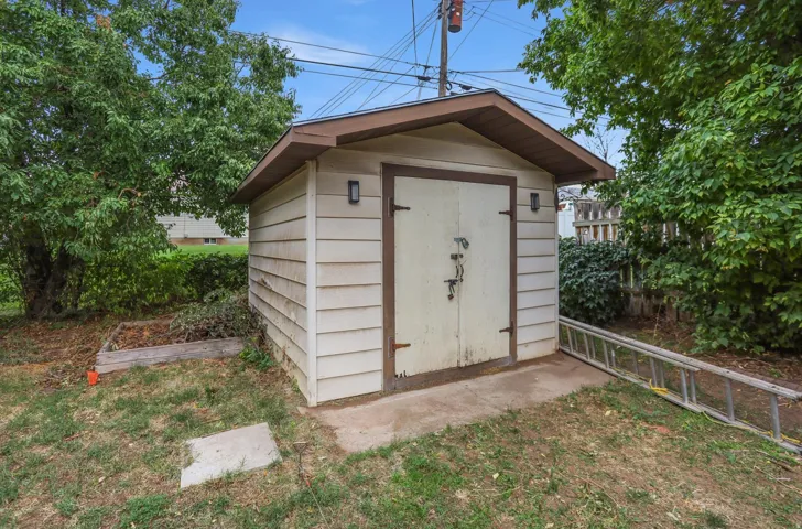 Utility shed with horizontal siding, a gabled roof, and double doors