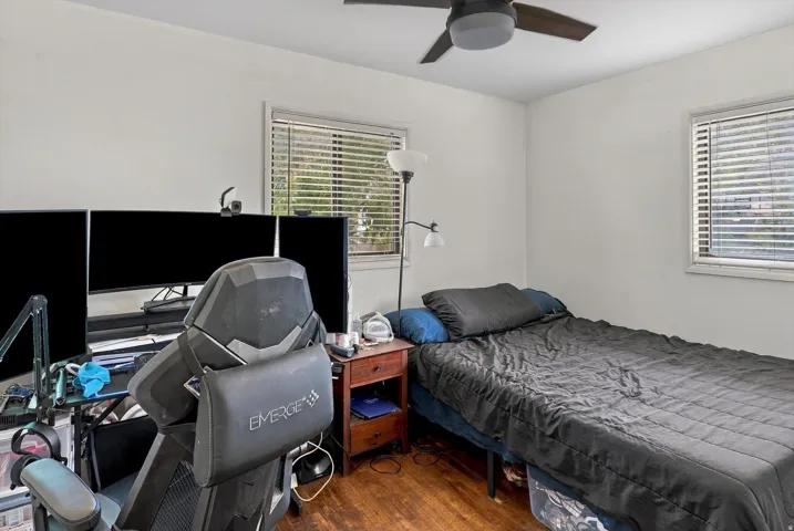 Hardwood flooring, white walls, and a ceiling fan with integrated lighting