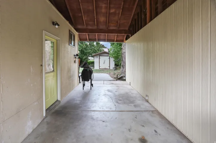 Covered concrete patio with exposed wood ceiling beams and a board-and-batten style accent wall