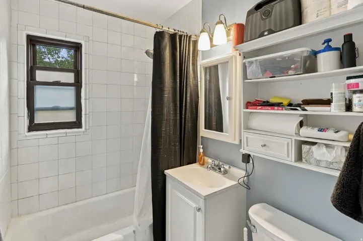 Bathroom featuring a white subway tile surround, built-in bathtub, and a vanity with an integrated sink