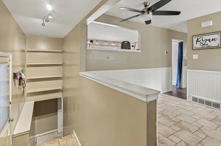 Built-in shelving, track lighting, ceiling fan, pass-through window, and wainscoting details
