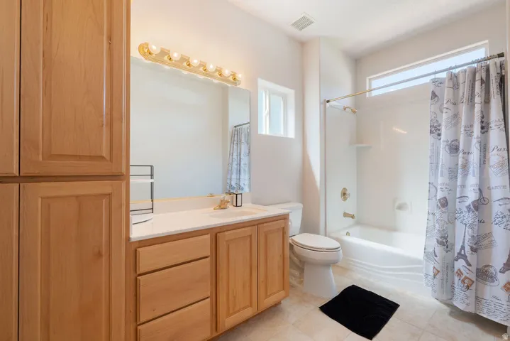 Bathroom featuring a single vanity with wood-finish cabinetry, white countertop, and integrated sink