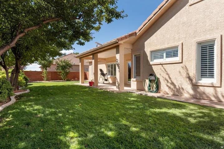 Expansive green lawn with mature landscaping and a covered patio