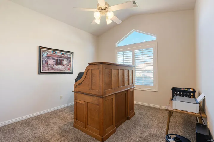 Carpeted room featuring a vaulted ceiling with a ceiling fan