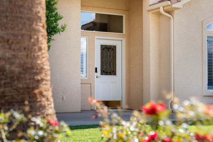 Stucco exterior with a white entry door, decorative glass insert, and transom window